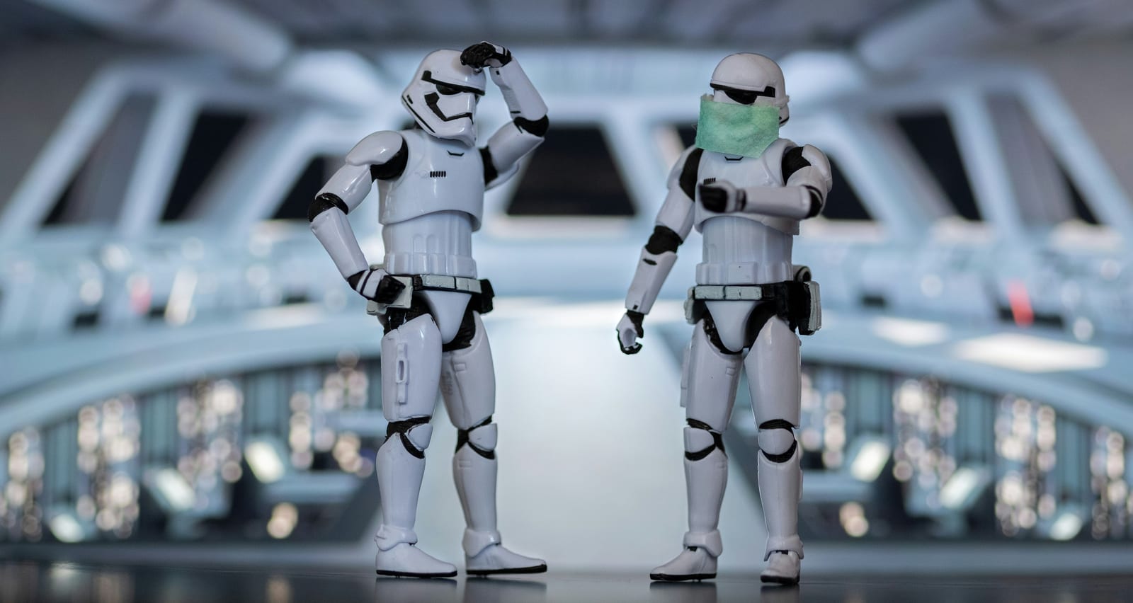 Two stormtrooper figures facing each other on a spaceship bridge, one scratching its helmet